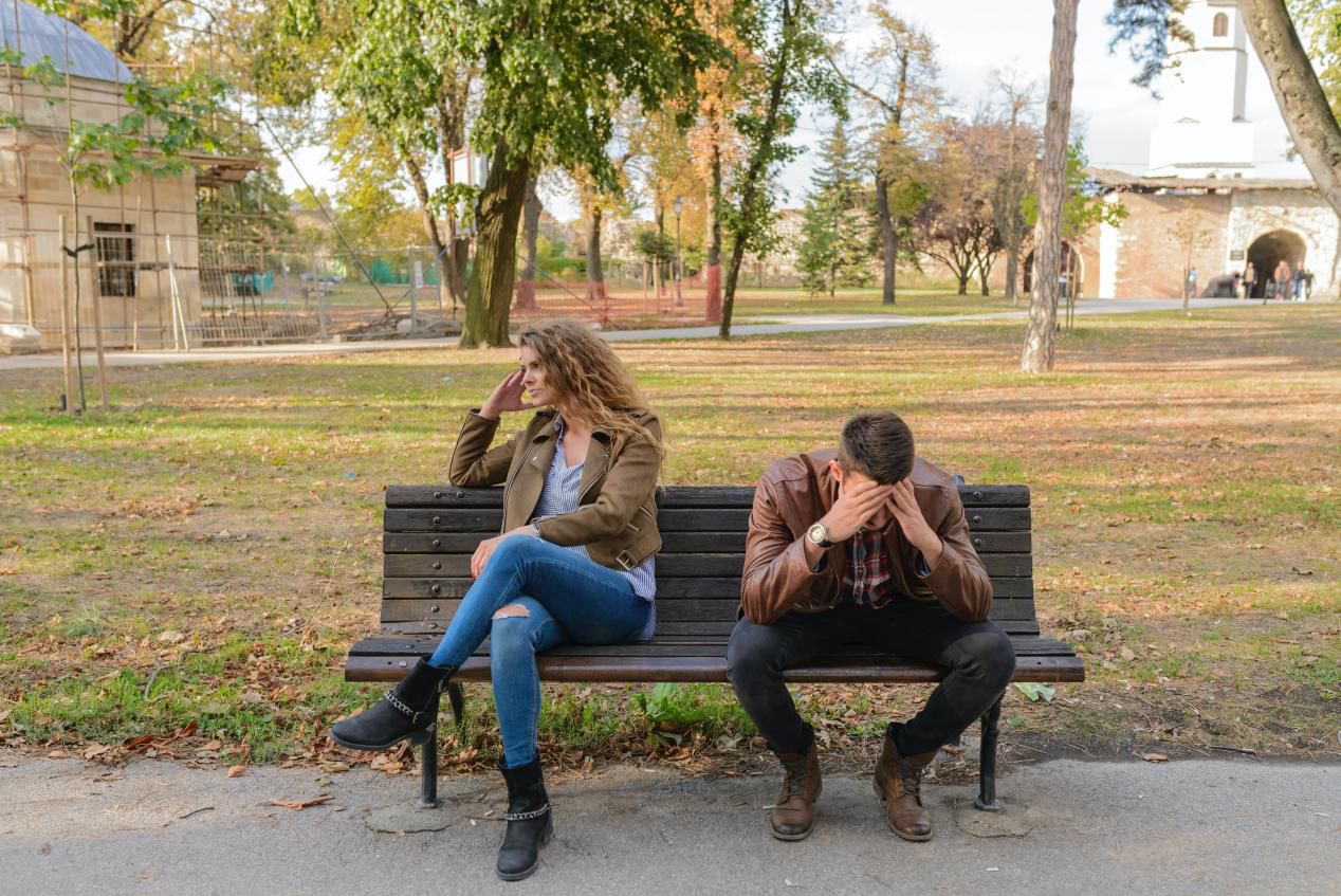 A couple is sitting on a bench in a park