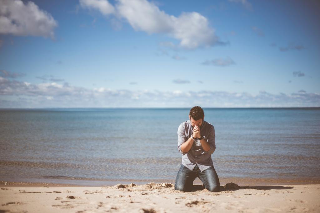 a man kneeling down near shore.