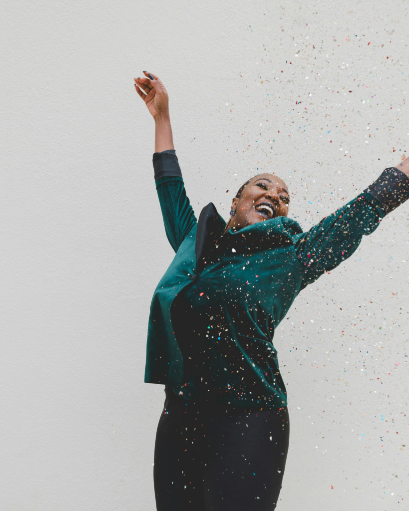 A woman in green jacket throwing confetti.