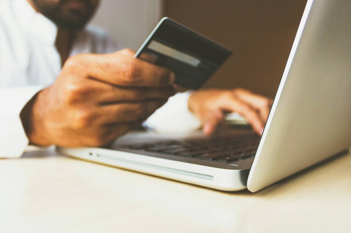 A person holding a credit card while using a laptop.