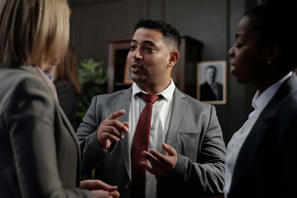 A man in a suit and tie talking to two women.