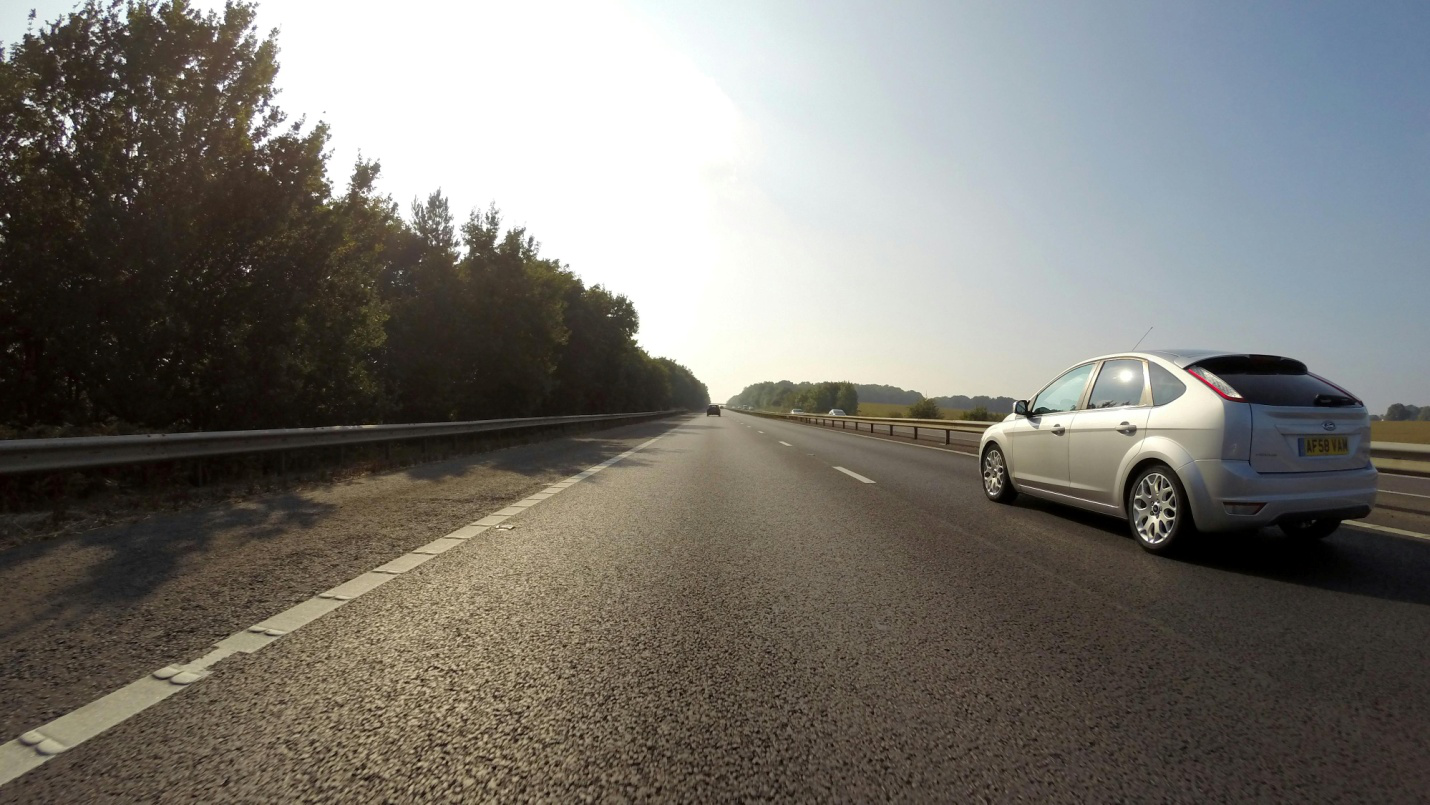 A car driving down the road on a sunny day.