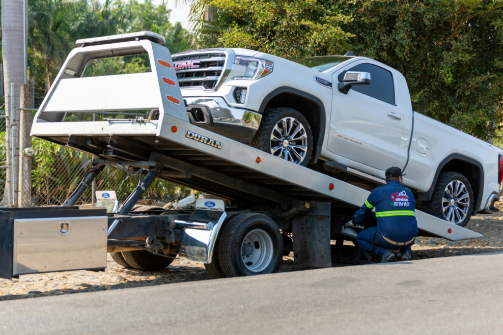 A tow truck is carrying a white pickup.