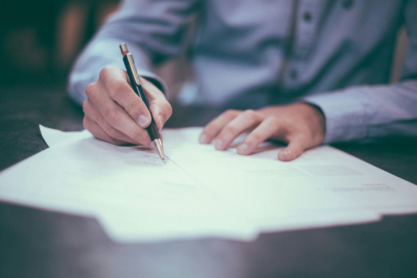 A person writing on paper with a pencil.