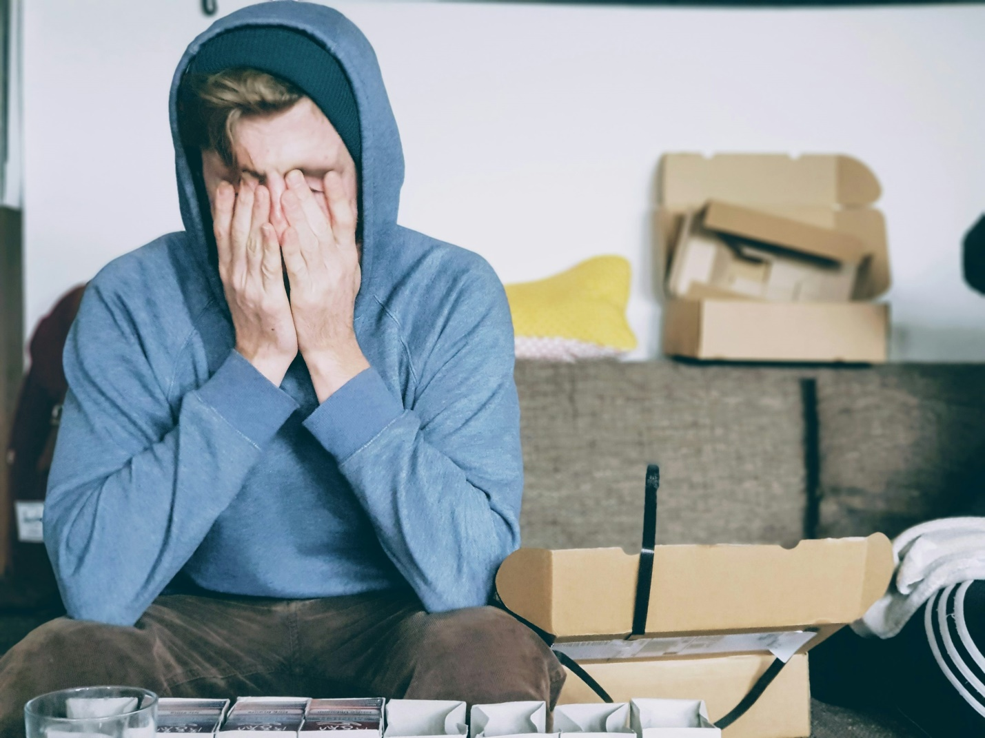 A man sitting on the floor with his hands covering his face.