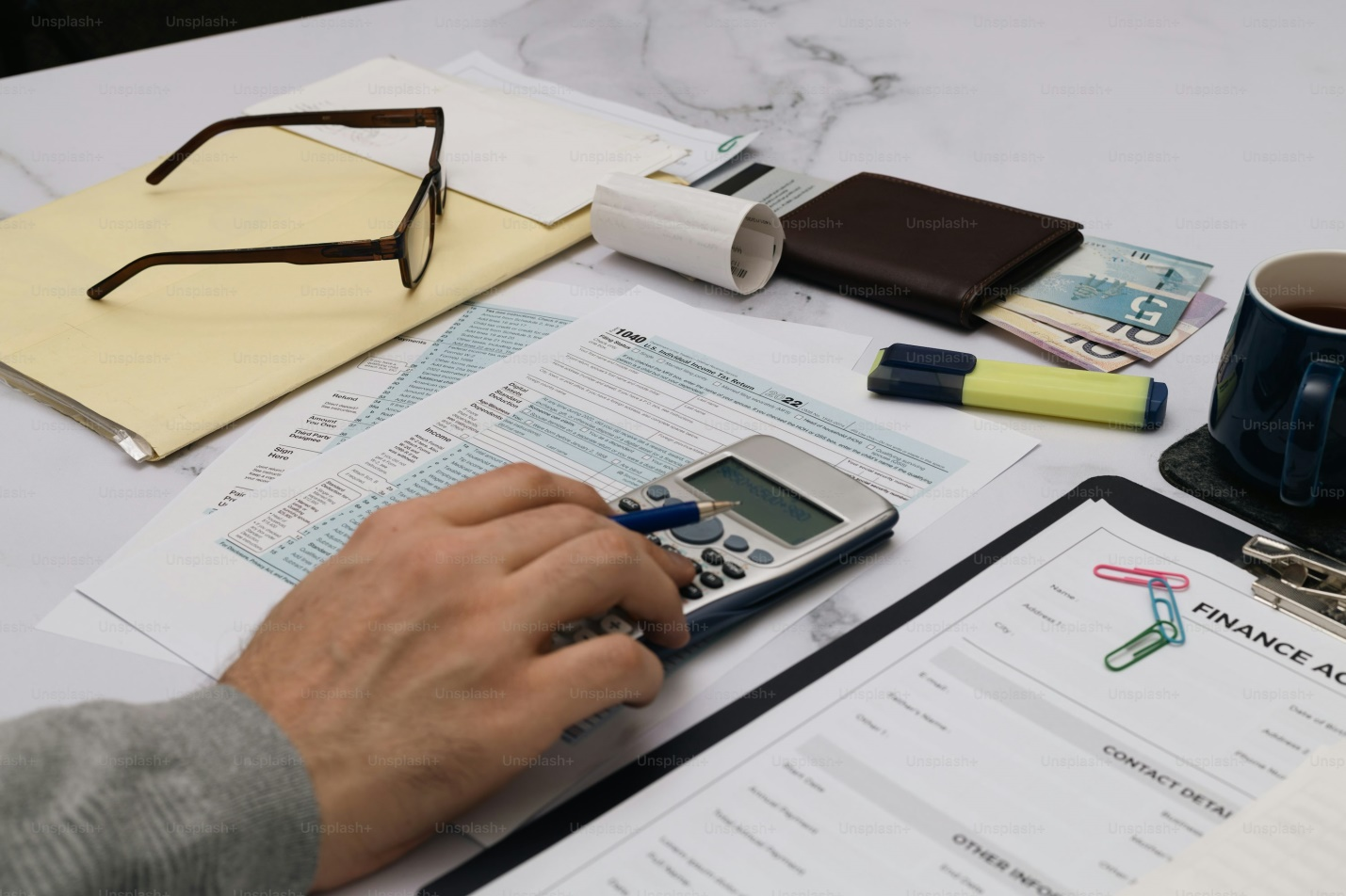 A person is using a calculator on top of papers.