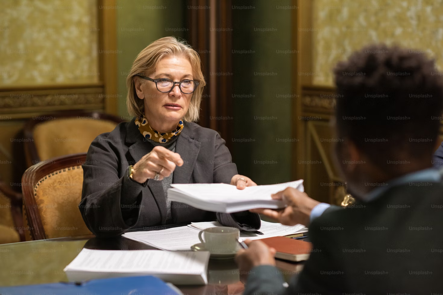 A woman sitting at a table with papers in front of her.