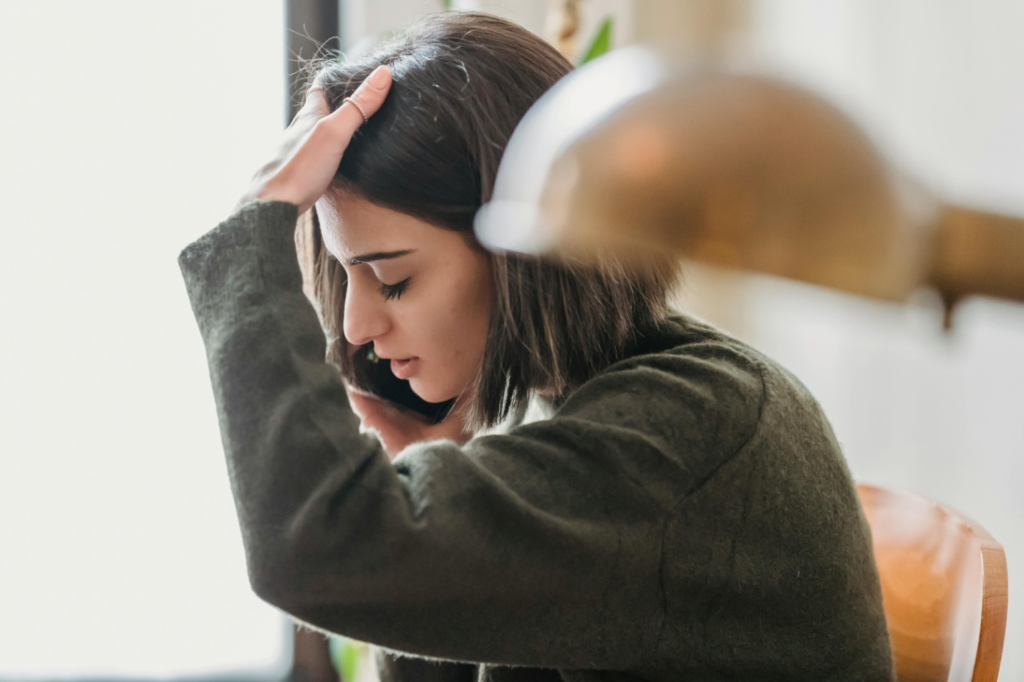 A woman is talking on her phone while holding her head.