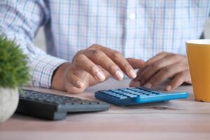 A person using a calculator on top of a table.