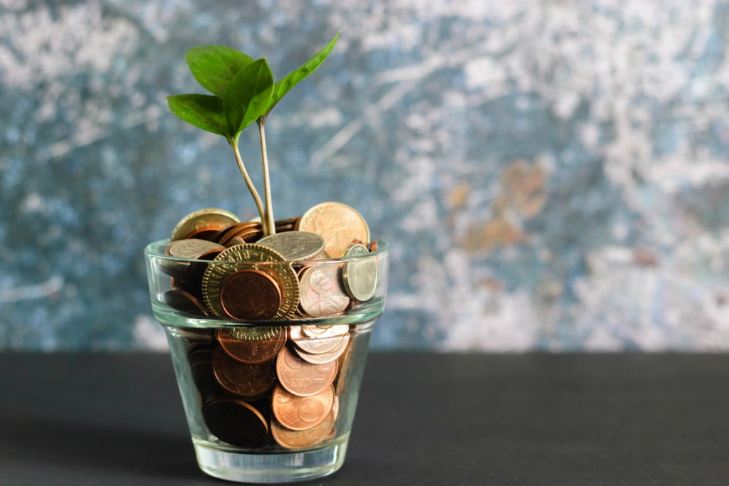 A glass cup filled with coins and a plant.