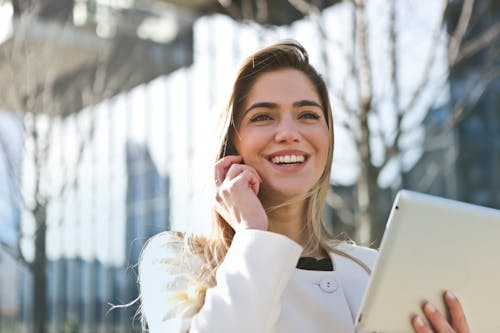 A woman holding an ipad and talking on the phone.