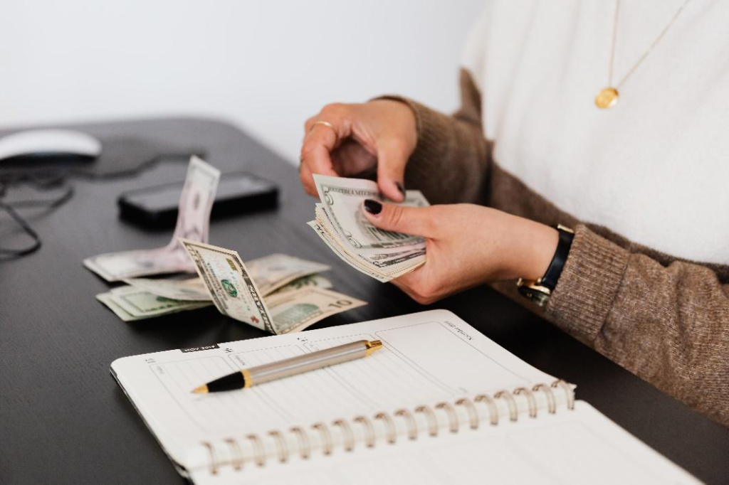 A person is counting money on top of the table.