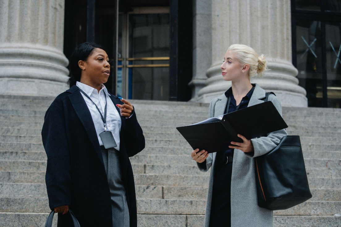 Two women standing on a set of steps talking.