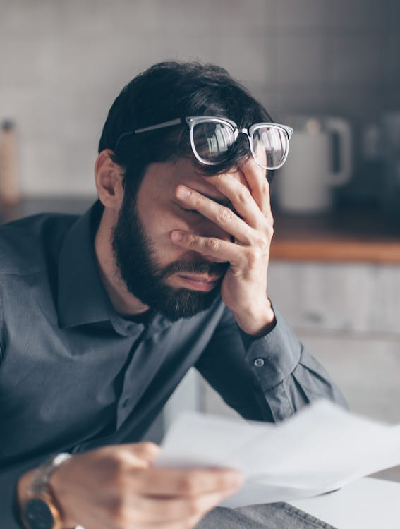 A man with glasses is holding his head