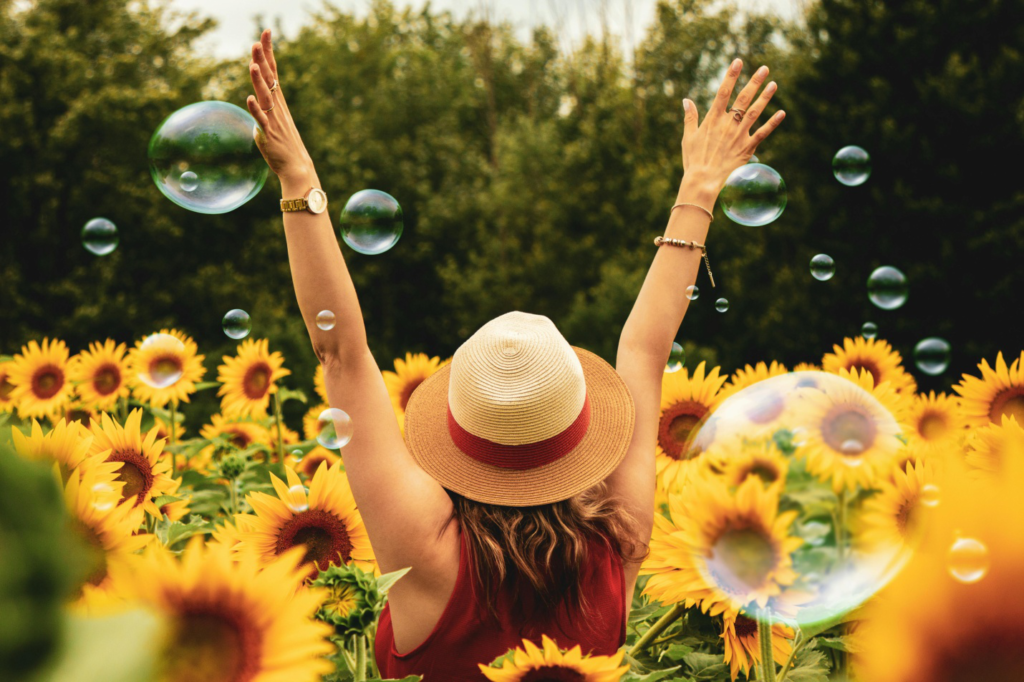 A woman in a field of sunflowers with bubbles