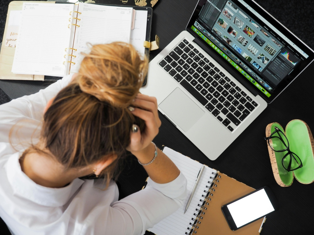 A woman sitting at her desk with her head in her hand.