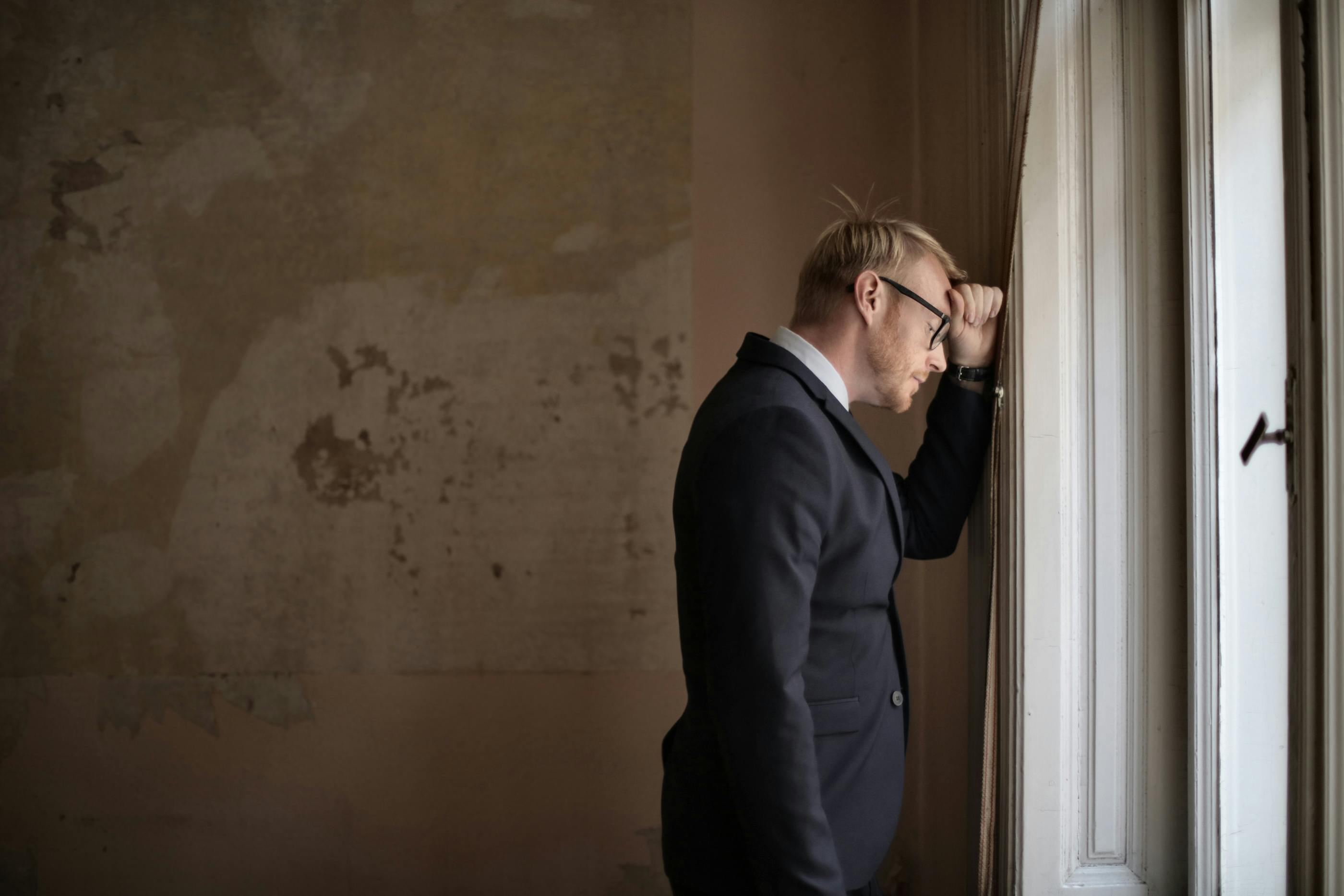 A man in a suit leaning against the wall