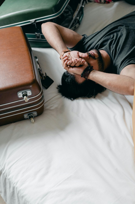 A man laying on the bed with his hands clasped together.