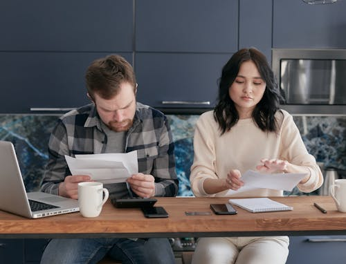 A man and woman sitting at a table with papers.