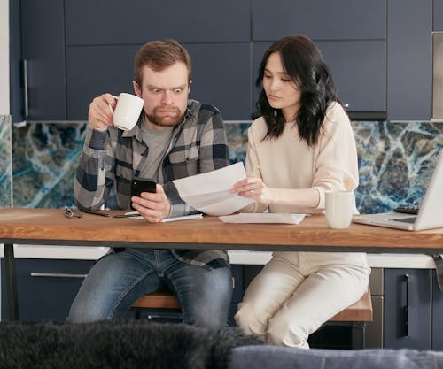 A man and woman sitting at a table looking at papers.