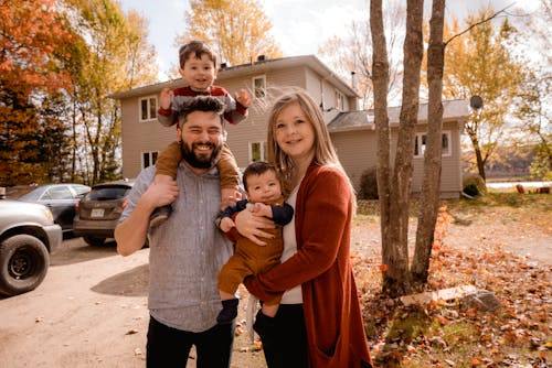 A family of four standing in front of their home.