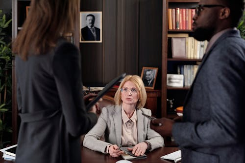 A woman sitting at a desk with two men.