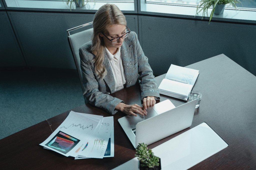 A woman sitting at a desk with papers and a laptop.