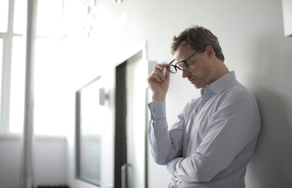 A man in glasses looking down at his face.