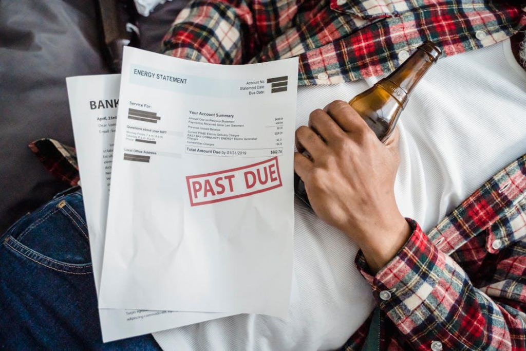 A person holding a bottle of beer and papers