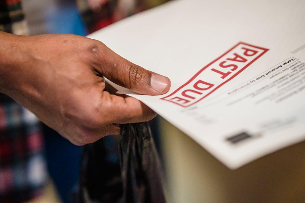 A person holding an envelope with the word " postal " on it.