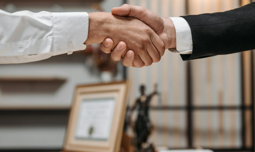 Two people shaking hands in front of a law office.