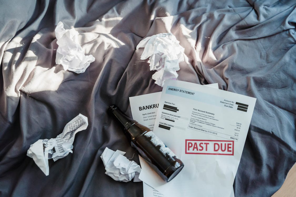 A bottle of beer and papers are on the bed.