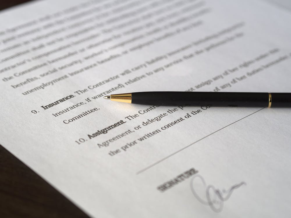 A man in a suit writing on paper with a pen.