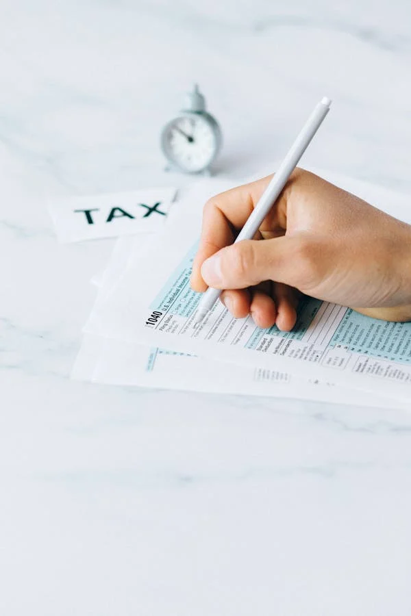 A person carefully filing tax documents at a desk.