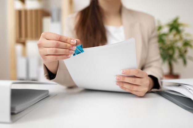 A woman applying a binder clip to sheets of paper