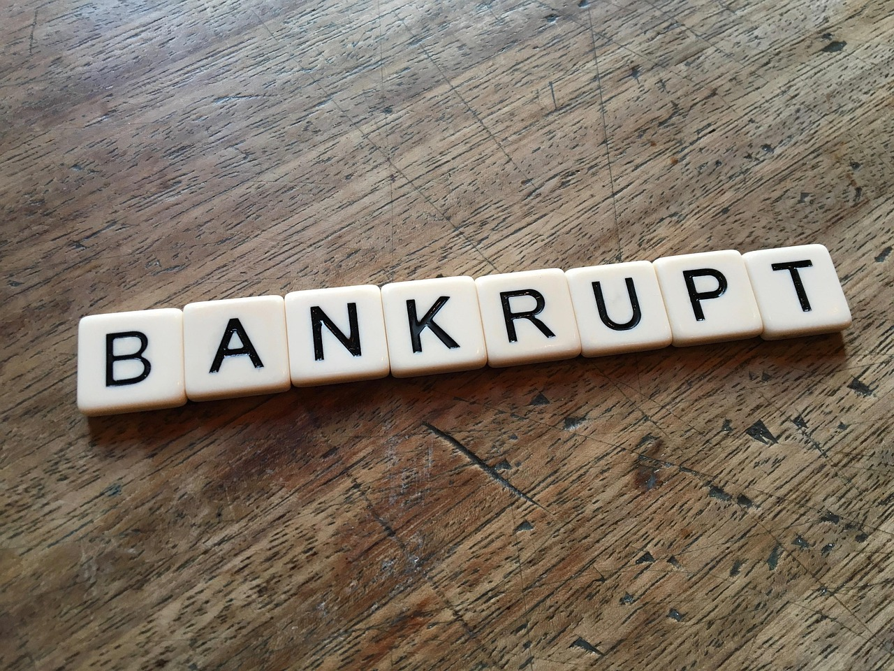 scrabble letters arranged on wooden table to say "Bankrupt"