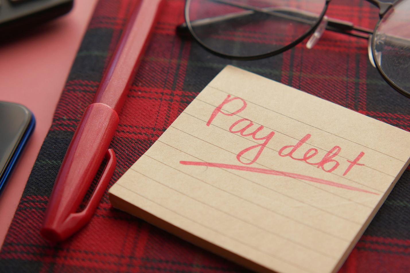 a sticky not with “pay debt” written on it
