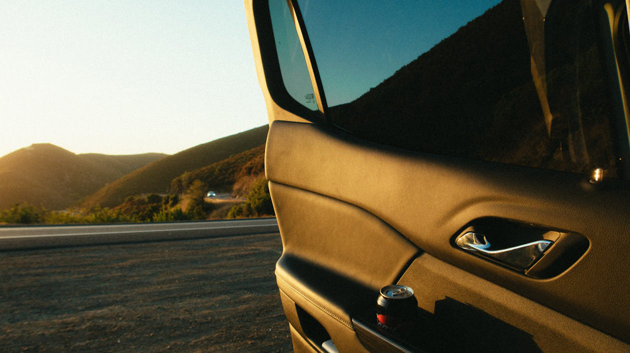 A parked car with the driver's door open on the side of a quiet road.
