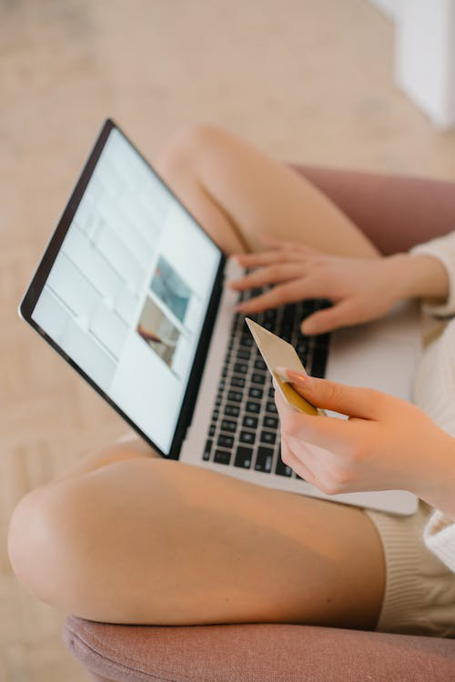 A person using a laptop while holding a credit card, suggesting online financial activity.