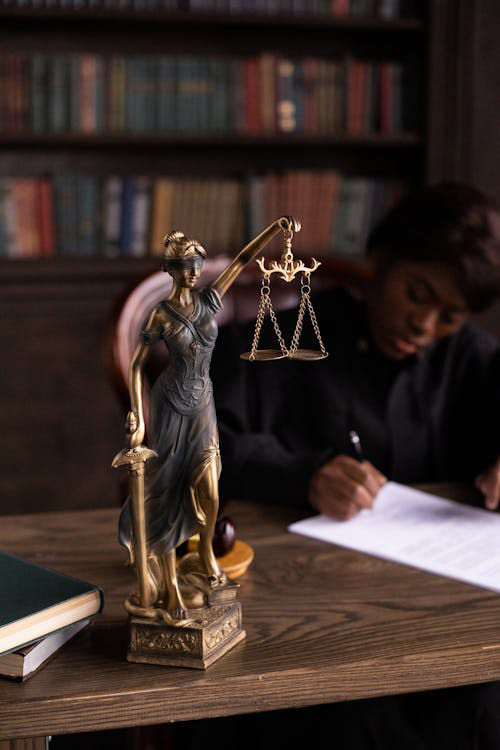 Close-up shot of a figurine representing Lady Justice with scales and a sword.