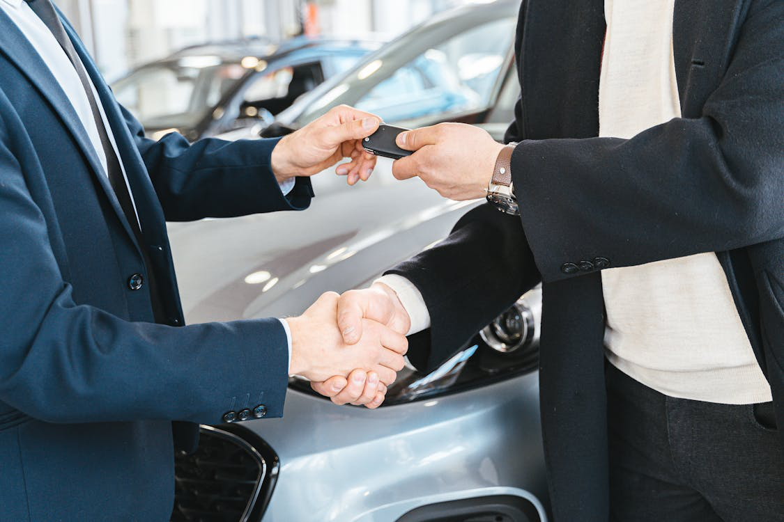 One person handing car keys to another during a handshake.