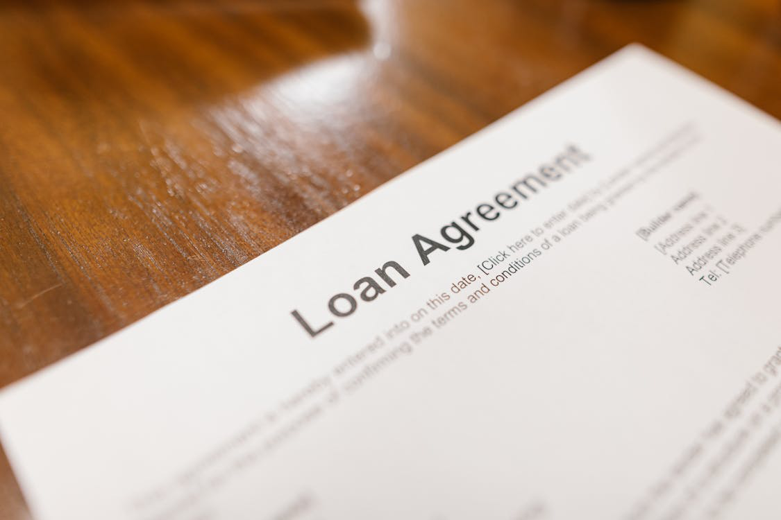 Close-up view of a loan agreement paper, with pen and hand in frame.