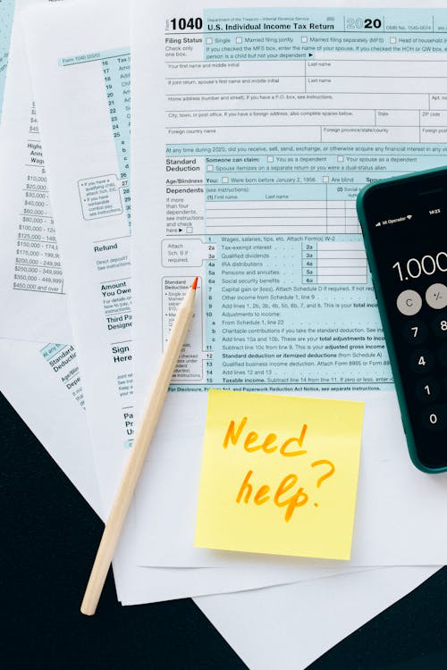  A view of tax paperwork, envelopes, and pens on a table asking for help.