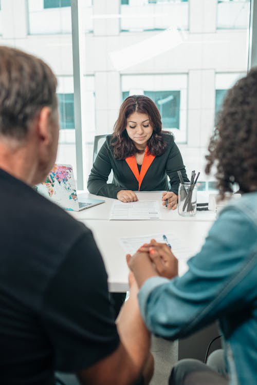  A woman holding documents while sitting next to a man, both focused on reading the paperwork