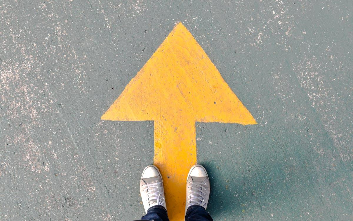 Person standing on an arrow pointing forward 