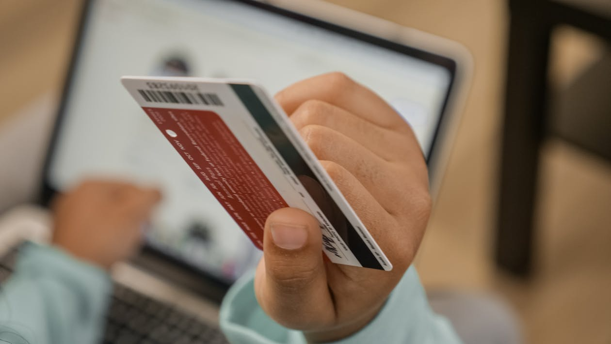 a person holding a credit card over their laptop