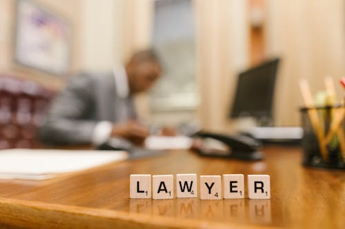 A repossession lawyer at a desk with Scrabble tiles spelling “LAWYER”