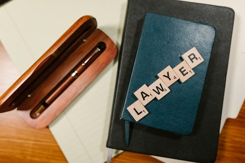 Documents with notebook glasses and scrabble tiles spelling “LAWYER”