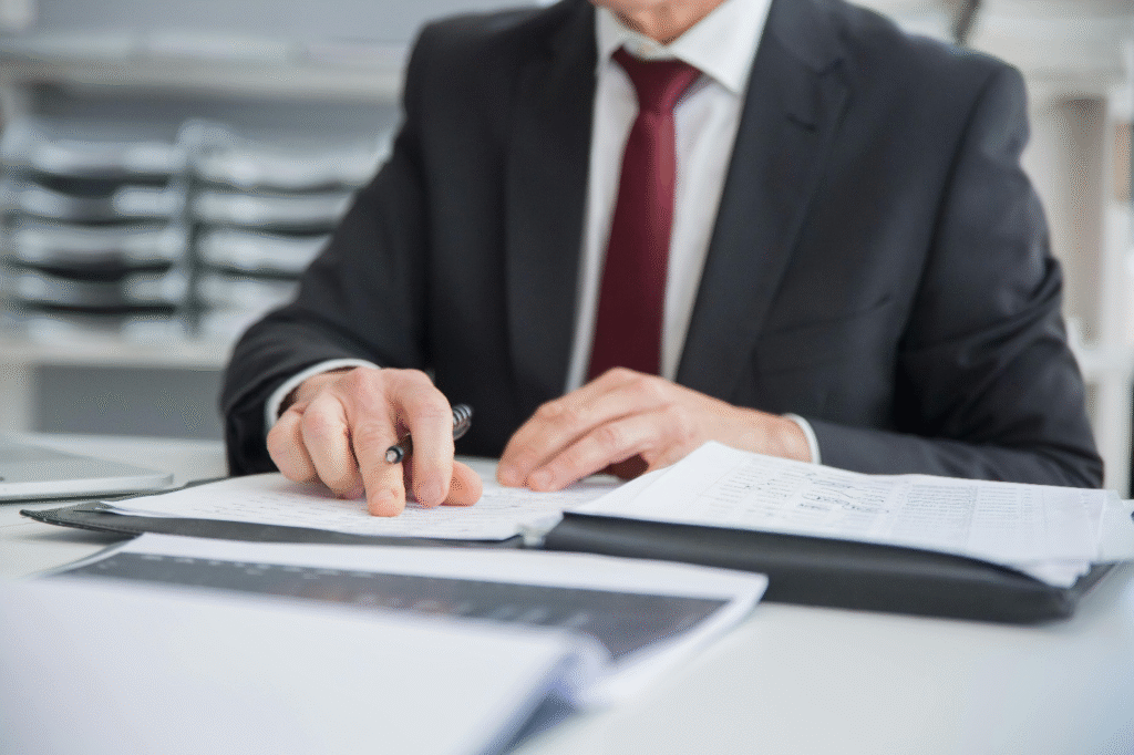 : A professionally dressed man reviewing financial documents and notes in an office setting