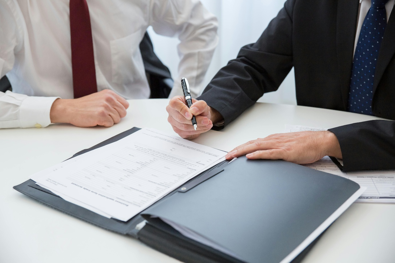 a person holding a pen near the documents on the table